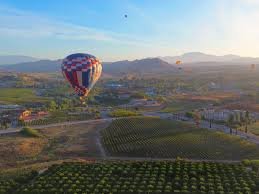 A hot-air balloon drifting over Temecula's vineyards and rolling hills at sunrise