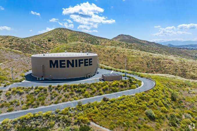 The landmark MENIFEE water tank set among green rolling hills above the city