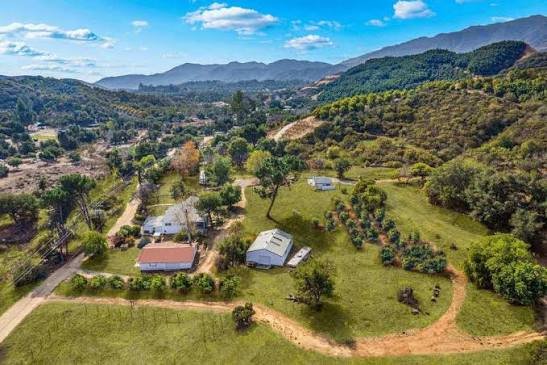 Aerial view of a rural Fallbrook, California property surrounded by hills and greenery