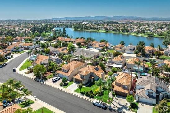 Aerial view of Menifee, California — tile-roof neighborhoods beside Heritage Lake with the hills beyond