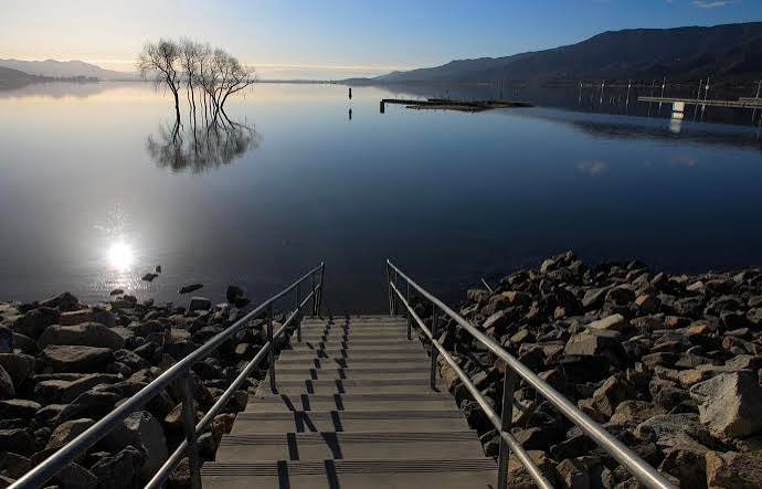 A boardwalk stairway leading down to the calm waters of Lake Elsinore at dawn
