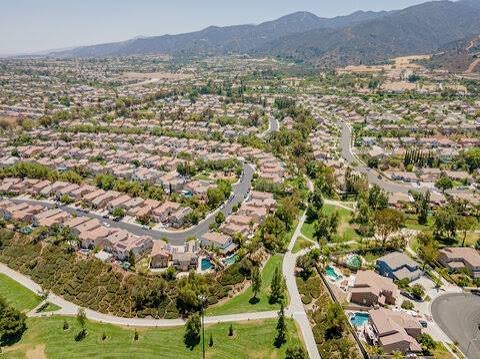 An aerial view of Corona, California neighborhoods with the Santa Ana Mountains rising behind them