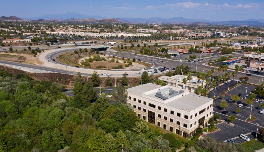 An aerial view of a Murrieta business district with a commercial office building and freeway