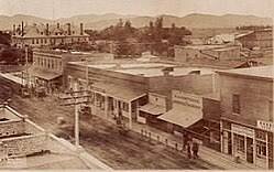 A historic sepia photograph of downtown Hemet, California, with early storefronts and the San Jacinto mountains beyond