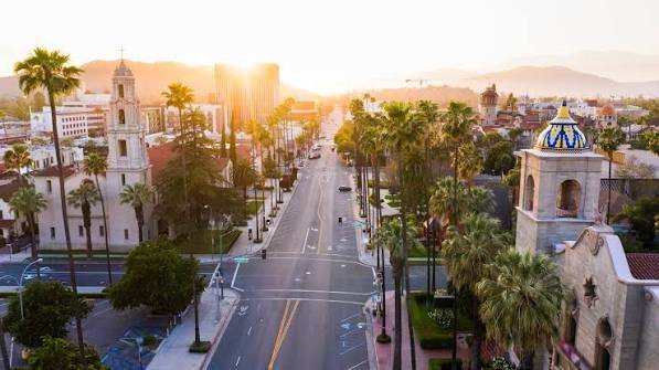 Downtown Riverside street lined with palm trees at sunset, with the Mission Inn in the background