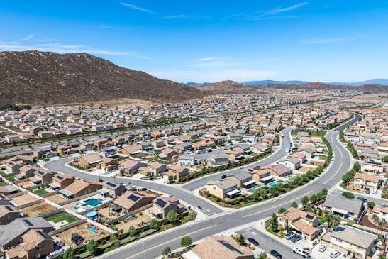 Aerial view of a Winchester master-planned neighborhood with rows of new homes, winding streets, and hills beyond