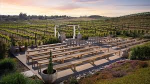 A vineyard estate and open-air event terrace overlooking the rows of a Temecula winery at dusk